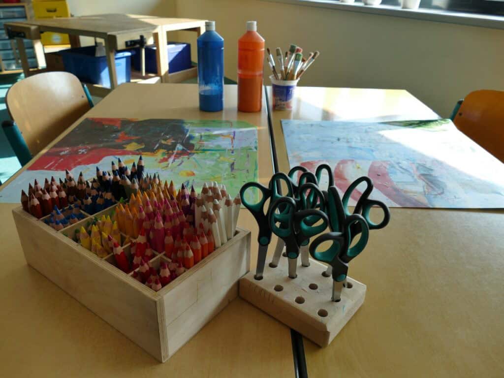 Tisch mit Buntstiften, Pinseln und Farbe und Scheren im Hort am Haasenweg