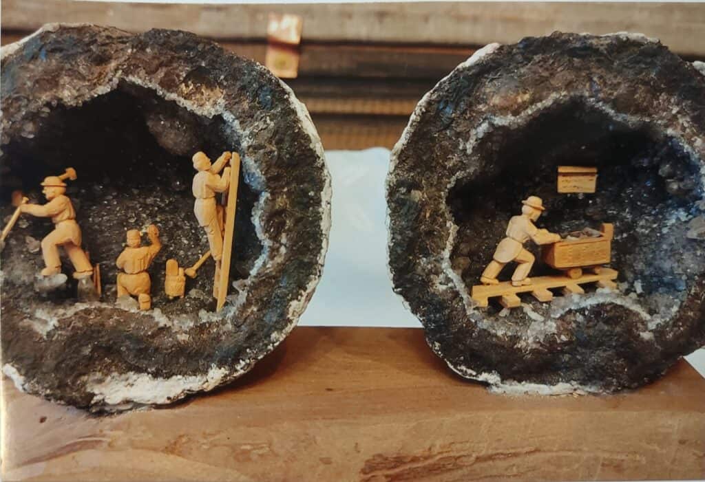 Zwei Drusen mit geschnitzten Bergleuten, die ihrer Arbeit nachgehen. In der Linken Druse wird Erz abgebaut und in der rechten Druse wird es in einem Hunt aus dem Schacht gebracht.